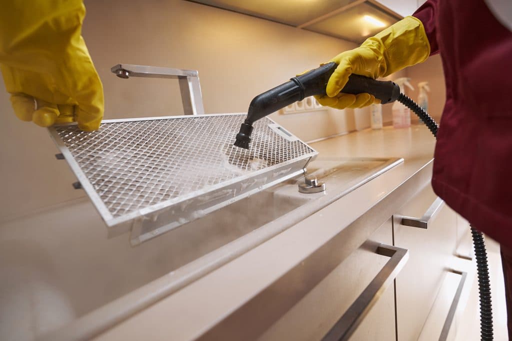 Limpeza profissional de equipamento em aço inox numa cozinha.
